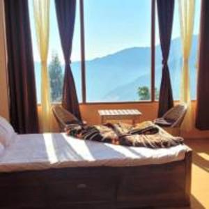 a bedroom with a bed with two chairs and a window at Mangpo Bliss Homestay By StayApart in Mangpu