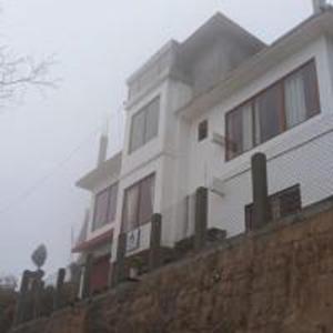 a white house on top of a brick wall at Mangpo Bliss Homestay By StayApart in Mangpu