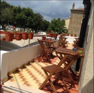 eine Terrasse mit Tischen und Stühlen auf dem Balkon in der Unterkunft Triglav Studio Apartments in Punat