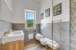 Un baño con lavabo, inodoro y ventana. en Casa Tramonti - Happy Rentals, en Gemonio