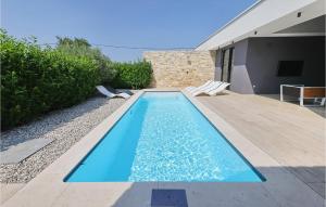 a swimming pool with two chairs next to a house at Villa K4 in Zadar