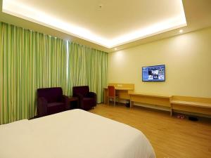 a room with a bed and a desk and a tv at 7 Days Inn Fucheng Wu Gongci Gaodeng East Street Binjiang Road in Haikou