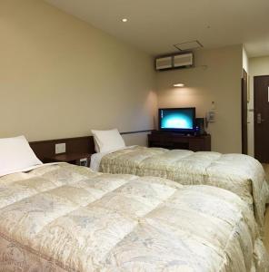 two beds in a room with a flat screen tv at Hakata Yufuin Takeo Onsen Manyo no Yu in Fukuoka