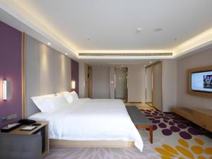 a bedroom with a large white bed and a flat screen tv at Lavande Hotel Yantai Train Station Branch in Yantai +130 photos