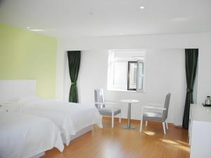 a bedroom with two beds and a table and chairs at Shell Shuozhou Shuocheng District West Zhenhua Street Renmin Square Hotel in Shuozhou