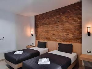 two beds in a room with a brick wall at Sabai @ Chiang Rai in Chiang Rai