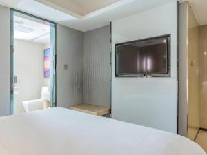 a bedroom with a white bed and a flat screen tv at Lavande Hotels·Qingdao Wusi Square in Qingdao