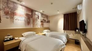 a hotel room with two beds and a painting on the wall at City Comfort Inn Zhuhai Qinglv Middle Road Riyuebei Grand Theater in Zhuhai