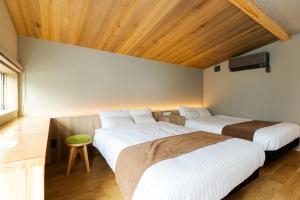 two beds in a room with wooden ceilings at TUGBOAT Suite in Osaka