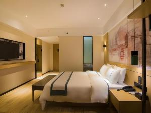 a hotel room with a large bed and a television at City Comfort Inn Hechi Tian'E Bus Terminal 