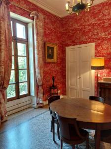 a dining room with a wooden table and red walls at Château de Livière in Calvisson