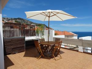 una mesa y sillas con una sombrilla en el balcón en Barreirinha Funcho House, en Funchal