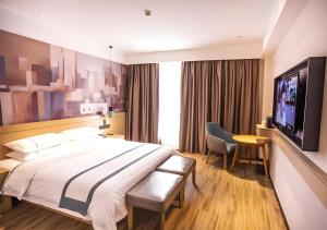 une chambre d'hôtel avec un grand lit et une télévision à écran plat dans l'établissement City Comfort Inn Nantong Qidong Renmin Zhong Road Xingfudao, à Huilongzhen
