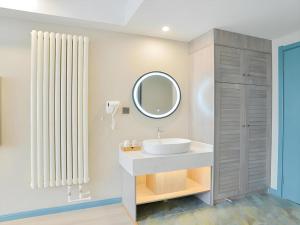 une salle de bain avec un lavabo et un miroir dans l'établissement Urban Garden Hotel Chengyang District Government Liuting Airport, à Qingdao 213 autres photos