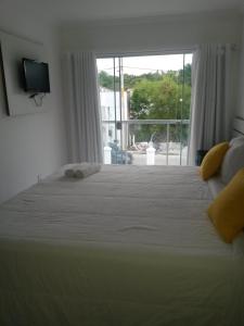 a bedroom with a large white bed with a window at Mont Carmelo Residencial Ap 5A Rede Tonziro in Porto Seguro +69 photos