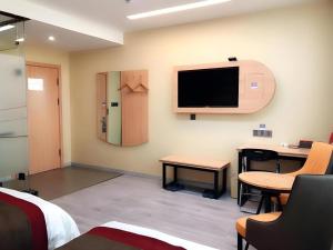 a room with a tv and a desk and a table at Thank Inn Hotel Inner Mongolia Baotou Donghe Haode Trade Plaza in Baotou