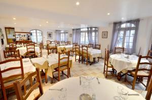 a restaurant with white tables and chairs and windows at Hôtel de l'Ours in Coulommiers