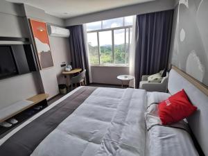 une chambre d'hôtel avec un grand lit et un canapé dans l'établissement Thank Inn Hotel Guangxi Qinzhou Lingshan Renhe, à Lingshan