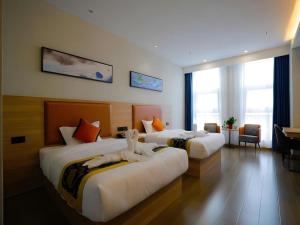a hotel room with two beds with towels on them at Green Tree Inn Express Tangshan Yueting County Bus Station in Laoting