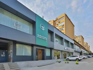 a building with a car parked in a parking lot at GreenTree Esports Hotel Qingdao Licang District Wanda in Laoshan