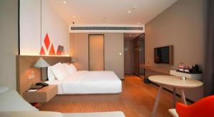 a hotel room with a white bed and a table at Borrman Hotel Zhonghsan Guzheng Huayi Plaza Light Rail Station in Zhongshan