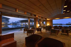 restauracja ze stołami i krzesłami oraz widokiem na wodę w obiekcie Kaike Grand Hotel Tensui w mieście Yonago