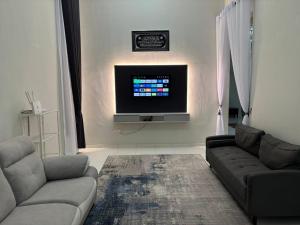 a living room with two couches and a flat screen tv at Friendly Homestay Malacca in Melaka