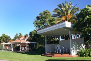 a pavilion with chairs and a table in a yard at Pacific Palms Resort in Papamoa