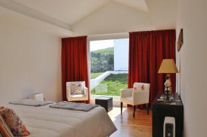 a bedroom with a bed and a large window at Aldeia do Priolo in Nordeste