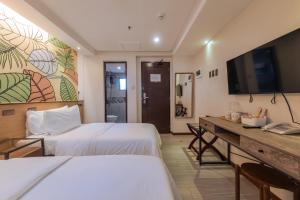 a hotel room with two beds and a flat screen tv at Maharlika City Inn in Bacolod
