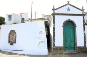 a white building with a green door and a sign at Aldeia do Priolo in Nordeste