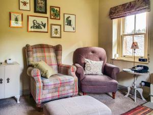 a living room with two chairs and a ottoman at Penny Cottage in Bonsall