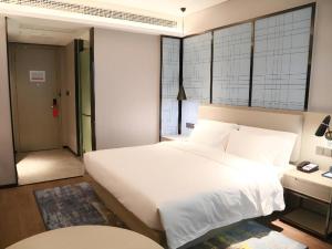 een slaapkamer met een groot wit bed en een raam bij Echarm Hotel Huanggang Tuanfeng Administration Service Center in Luotian +22 foto's