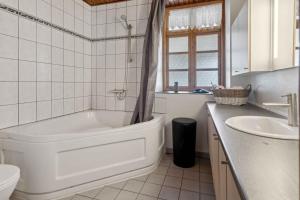 a white bathroom with a tub and a sink at Large Holiday Home Near Tønder in Tønder +27 photos