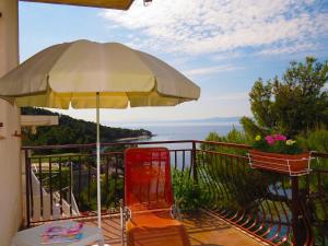 an umbrella and chairs on a balcony with a view at Apartments Pino Brela in Brela