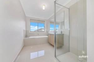 a white bathroom with a shower and a sink and a window at Exclusive Perfectly Big House by My Lodgingfy International in Clyde North +69 photos