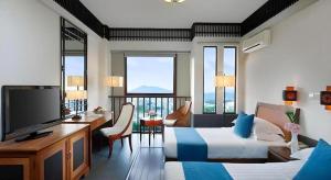 une chambre d'hôtel avec deux lits, un bureau et une télévision dans l'établissement International Asia-Pacific Convention Center, à Sanya