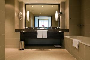 ein Badezimmer mit einer Badewanne, einem Waschbecken und einem Spiegel in der Unterkunft Holiday Inn Almaty, an IHG Hotel in Almaty