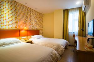 a hotel room with two beds and a flat screen tv at Home Inn Tianjin Weidi Avenue Culture Centre in Tianjin