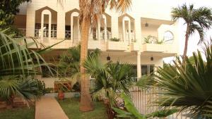 a building with palm trees in front of it at B & B Le Nomade in Ouagadougou