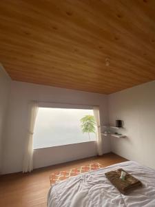 a bedroom with a bed and a large window at Glamping Visit Telaga Menjer in Garung