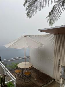 a table and two chairs under an umbrella on a deck at Glamping Visit Telaga Menjer in Garung