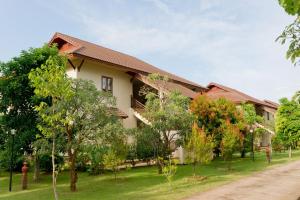 ein Gebäude mit vielen Bäumen davor in der Unterkunft Teak Garden Resort, Chiang Rai in Chiang Rai