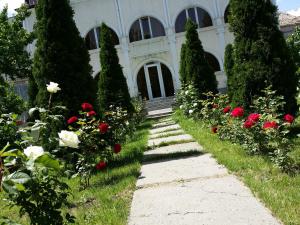 un camino en un jardín con rosas y árboles en Palma Palace Hotel, en Ereván