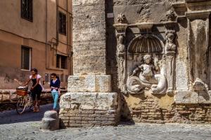 a woman standing next to a stone wall with a statue at Palazzo Medusa in Rome