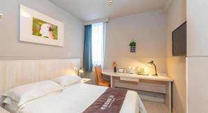 a bedroom with a bed and a desk and a television at Jinjiang Inn Xi'an Dayan Tower Xiaozhai Metro Station in Xi'an +43 photos