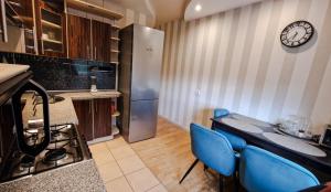 a kitchen with a table and blue chairs and a refrigerator at Erdvus 3 kambarių butas Ventos 22 in Mažeikiai