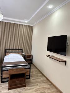 a bedroom with a bed and a flat screen tv at Kushchu Guest House in Bishkek
