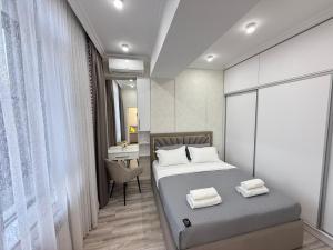 a bedroom with a bed and a desk with a chair at NOVA apartment BayTash Tower near TSUM and GUM in Bishkek