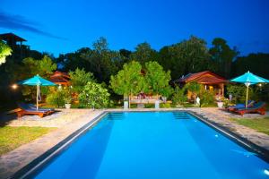 una piscina con dos sombrillas y sillas azules en Shangri-Lanka Village, en Tissamaharama